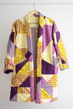 a colorful coat hanging on a clothes line with white wall in the backround