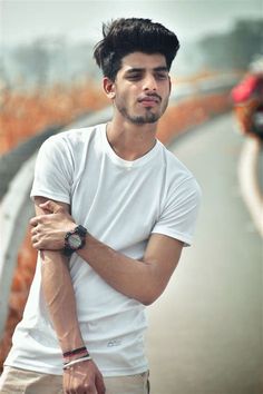 a man with his arms crossed standing on the side of a road