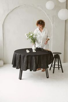 a woman standing next to a table with flowers on it