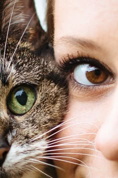 a close up of a woman holding a cat with her face next to her head