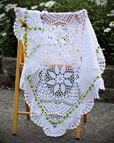 a white crocheted doily with an owl on it and flowers in the background