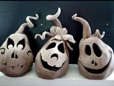 three clay pumpkins with faces carved into them