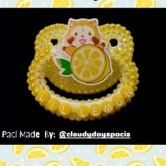 a close up of a brooch with lemons and a cat sitting on it