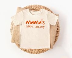 Details Mama's Little Turkey Natural Thanksgiving Tee Fabric has stretch Short sleeve style with a crew neckline Size newborn-18 months is a bodysuit style This style is made for growing babies, designed for comfort and easy changes. Youth 2T-Youth XL is a t-shirt style. It's designed with a classic crew neckline and features a burnt orange graphic, making it the perfect way to celebrate the holiday season in style. Material and Care 100% Cotton Materials may have natural variations Colors may v Thanksgiving Attire, Turkey Illustration, Turkey Print, Bodysuit Style, Orange Graphic, Thanksgiving Tee, Turkey Shirts, Holiday Attire, Thanksgiving Shirt