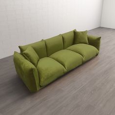 a green couch sitting on top of a hard wood floor next to a white wall