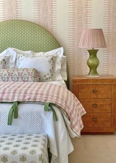 a bedroom with pink and green wallpaper, white bedding and a checkered bedspread