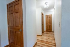 an empty hallway with wooden doors and hard wood flooring on either side of the door