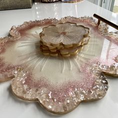 pink and gold glass plates on a white table with a brush in the middle, sitting on top of each other