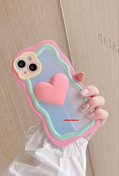 a woman holding up a phone case with a heart on it