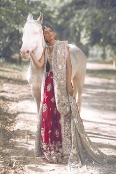 a woman standing next to a white horse