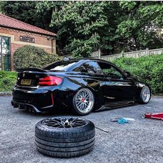 a black car parked next to a pile of tires