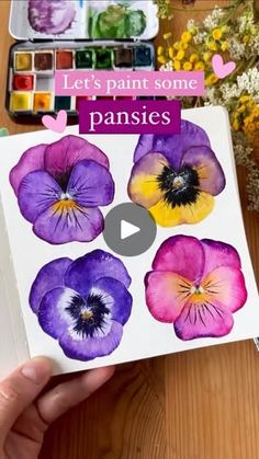 a person holding up a book with pansies on it and the title let's paint some pansies