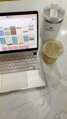 an open laptop computer sitting on top of a table next to a cup of coffee