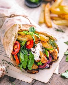 a pita filled with veggies and sauce on top of a wooden table