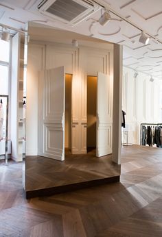 an empty room with white walls and wooden flooring in the foreground is a row of open closets