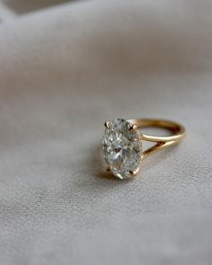 a close up of a diamond ring on a white cloth with the center stone in yellow gold