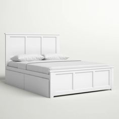 a white bed with two pillows on top of it