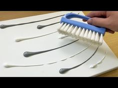 a hand holding a blue and white brush on top of a piece of paper that is shaped like toothbrushes