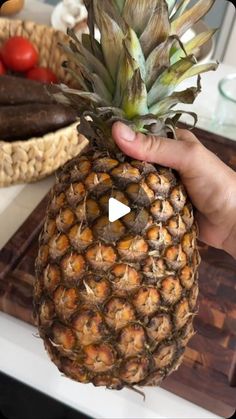 a person holding up a pineapple on top of a counter