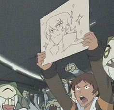 a man holding up a drawing in front of his face with other people behind him