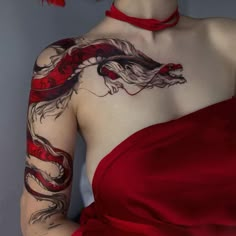 a woman wearing a red dress with dragon tattoos on her arm and shoulder, in front of a gray background