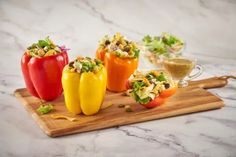 several peppers on a cutting board with some dressing in the middle and other ingredients around them