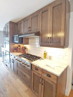 a kitchen with wooden cabinets and white marble counter tops, along with hardwood flooring