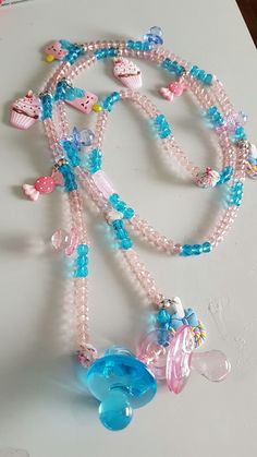 a necklace with beads and charms hanging from it's side on a table top