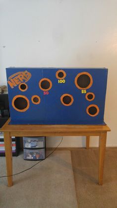 a wooden table topped with a blue and orange board game on top of carpeted floor