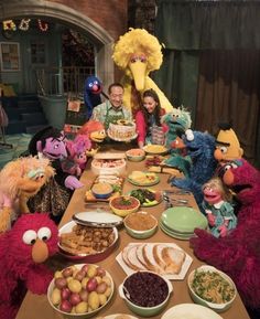 sesame street characters are sitting around a table with food