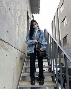 a woman wearing a face mask is standing on the stairs with her hand in her pocket