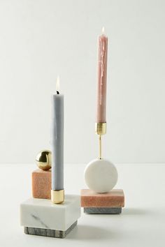 two candles are sitting on marble blocks