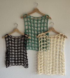 three different colored netted vests hanging on a wall