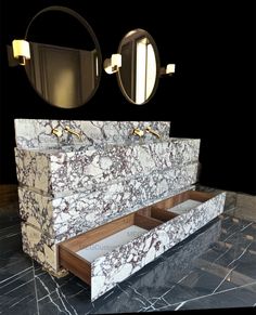 a bathroom with marble counter tops and two mirrors on the wall next to each other