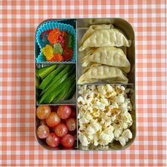 a bento box filled with different types of food on top of a checkered table cloth