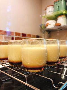 four glasses filled with liquid sitting on top of an oven