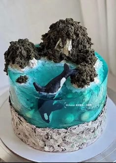 a blue and white cake with an orca on it's side, sitting on a plate