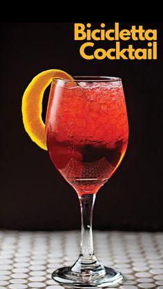 a glass filled with liquid sitting on top of a table next to an orange slice