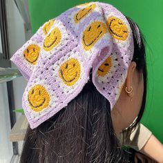 a woman wearing a crocheted hat with smiley faces on it