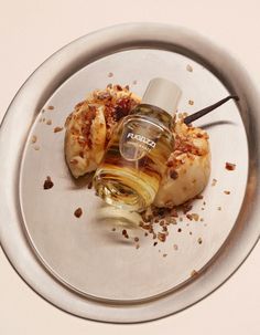 a silver plate topped with two pieces of food next to a bottle of perfume on top of it