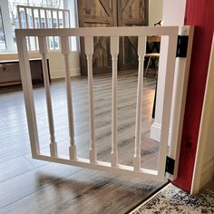 a red door and white railing in a room with hardwood floors, wood paneling, and sliding glass doors