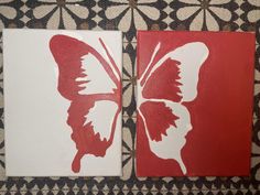 two red and white butterfly paintings sitting on top of a tiled floor next to each other