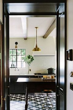 an open door leading to a kitchen with black and white tile flooring on the walls