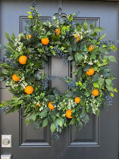 an orange wreath on the front door of a house with blue berries and greenery