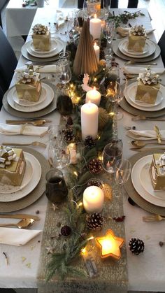 a table set for christmas with candles, plates and napkins on top of it