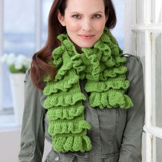 a woman standing next to a window wearing a green scarf