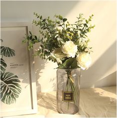 a vase filled with white flowers sitting on top of a table next to a framed photo