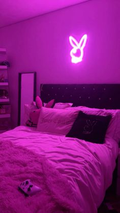 a bed in a room with pink lights and pillows on it's headboard