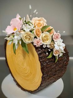 a cake decorated with flowers on top of a white plate in the shape of a log