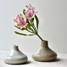 two white vases with pink flowers in them